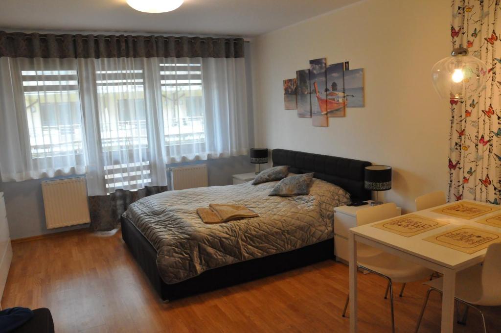 a bedroom with a bed and a table and windows at Apartament Motyl in Świnoujście