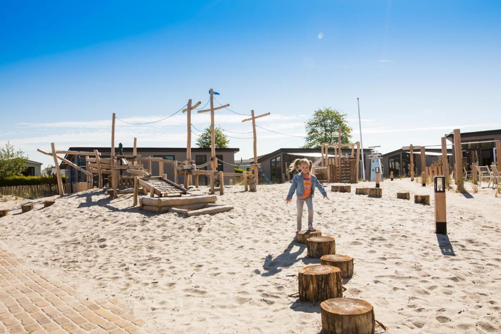 Una chica parada sobre tocones en un patio de recreo en EuroParcs Parc du Soleil en Noordwijk aan Zee