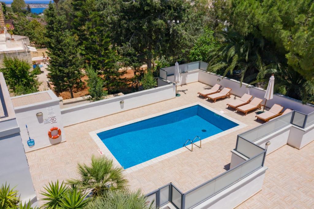 an overhead view of a swimming pool with two lounge chairs and a swimming pool at Baldacchino Holiday Villas in Mellieħa