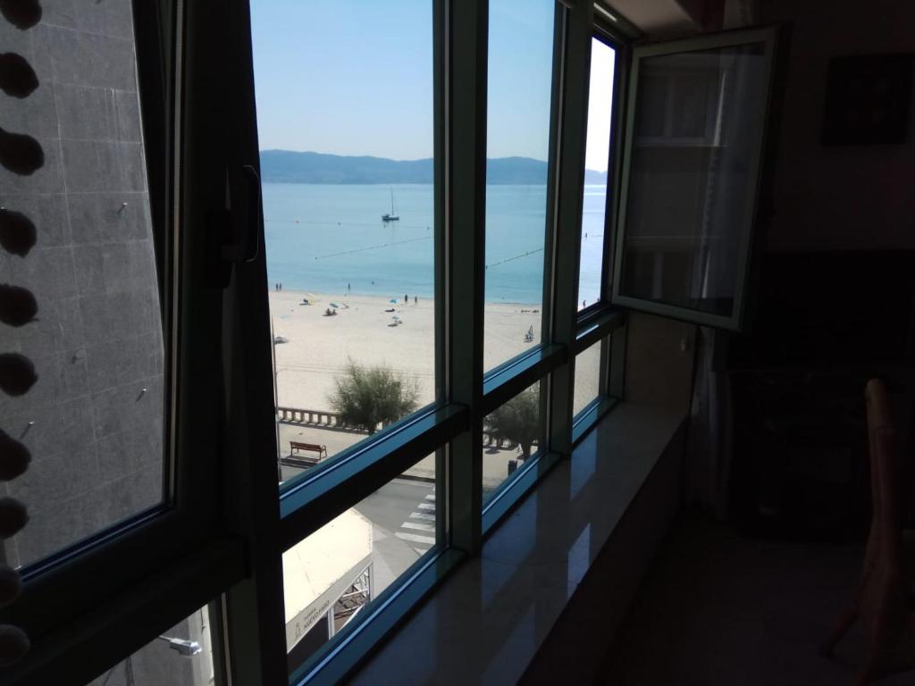a room with windows looking out at a beach at Apartamento A Peregrina (Silgar, Sanxenxo) in Sanxenxo