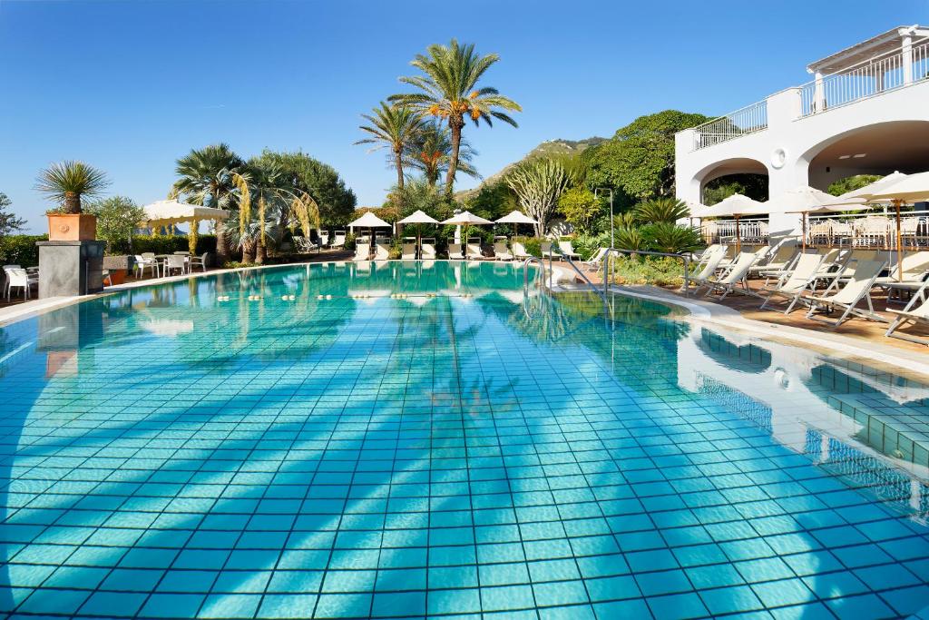 una piscina en un complejo con sillas y palmeras en Hotel Parco Smeraldo Terme, en Isquia