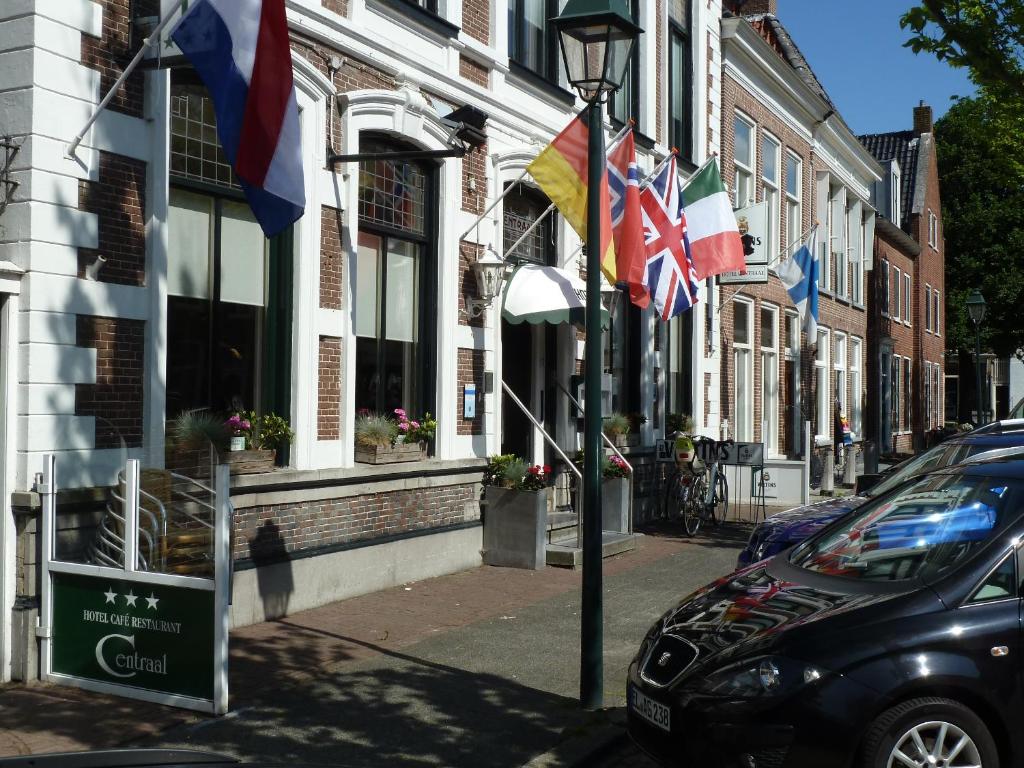 una strada con bandiere di fronte a un edificio di Hotel Centraal a Harlingen