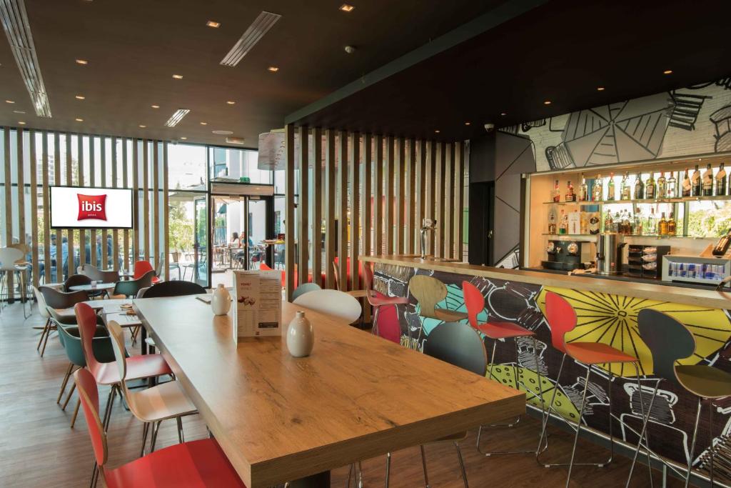a restaurant with a large wooden table and chairs at ibis Alger Aéroport in Alger