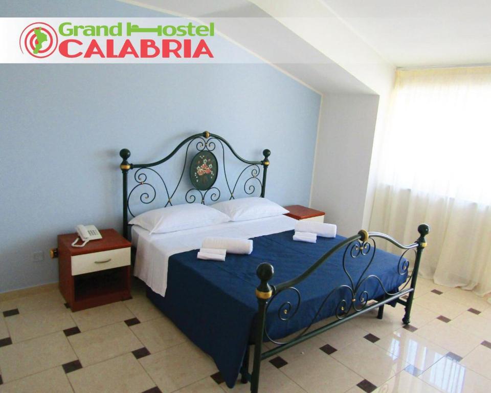 Grand Hostel Calabria في Pietrapaola: غرفة نوم بسرير ازرق وبيض ونافذة