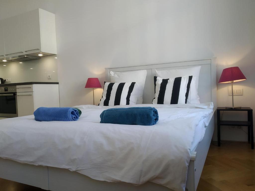 1 cama blanca grande con 2 almohadas azules. en Prague Saints Apartments, en Praga