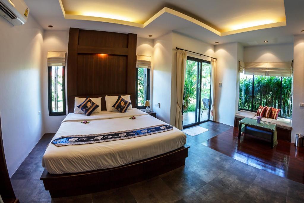 a bedroom with a large bed in a room with windows at Baan Armeen Cottage in Bang Tao Beach