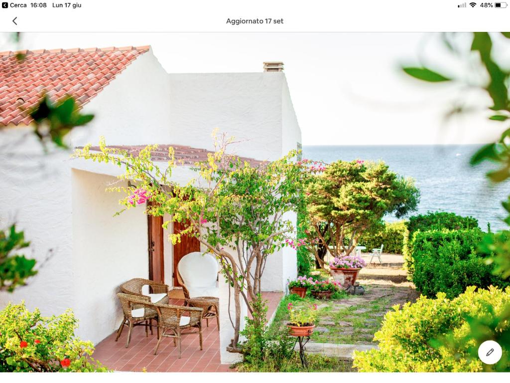 a white house with a patio with tables and chairs at Villetta sul mare a Punta Tramontana in Castelsardo