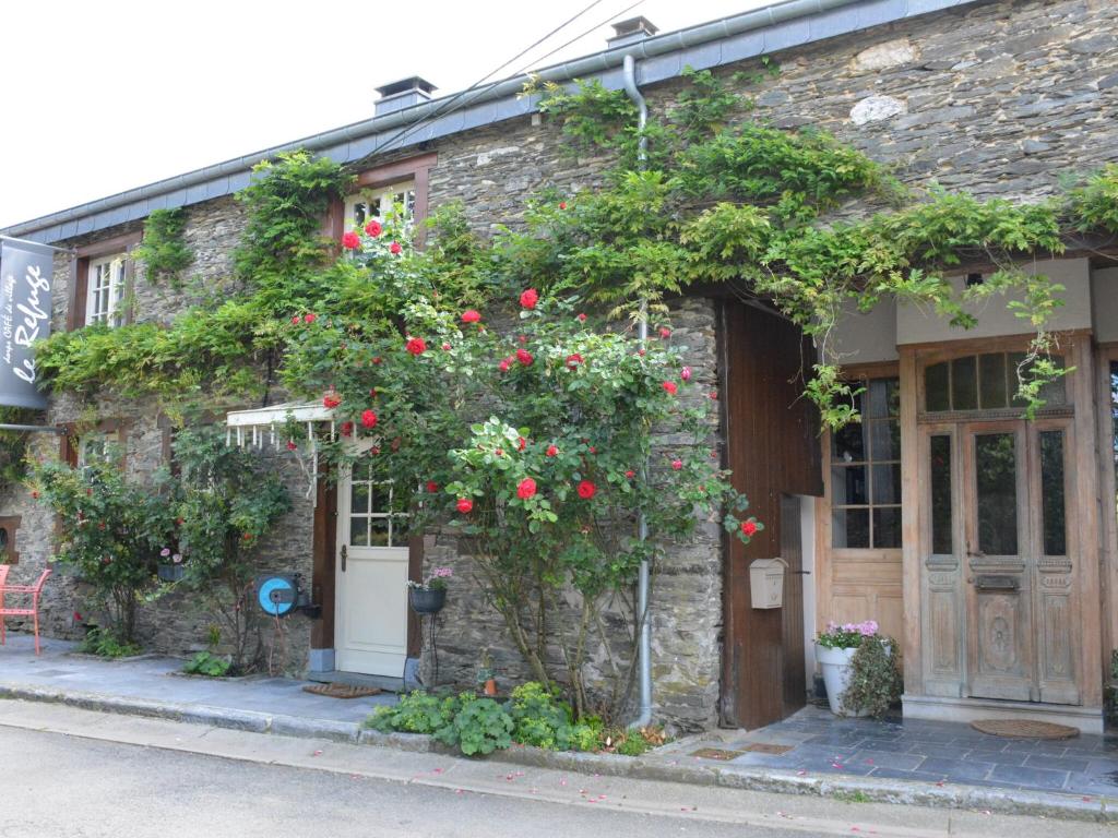 een oud stenen gebouw met rode bloemen erop bij Authentic Holiday Home located in Bievre with Jacuzzi in Bièvre