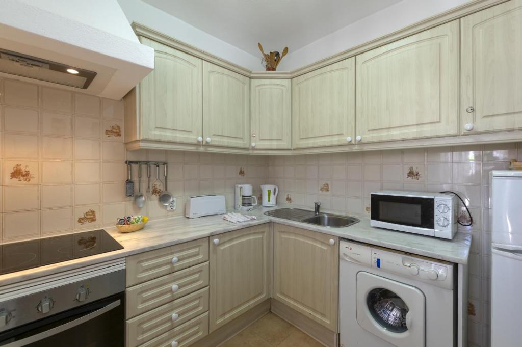 a kitchen with a microwave oven and a sink at Rocha Brava Village Resort in Carvoeiro