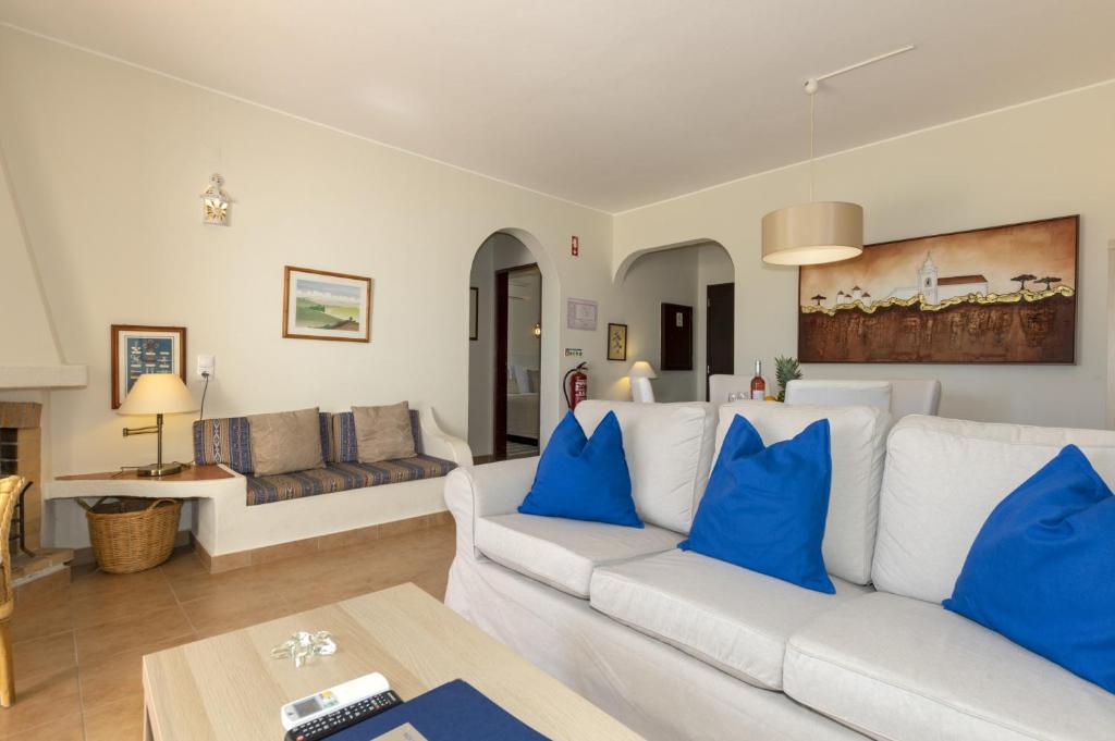 a living room with a white couch and blue pillows at Rocha Brava Village Resort in Carvoeiro