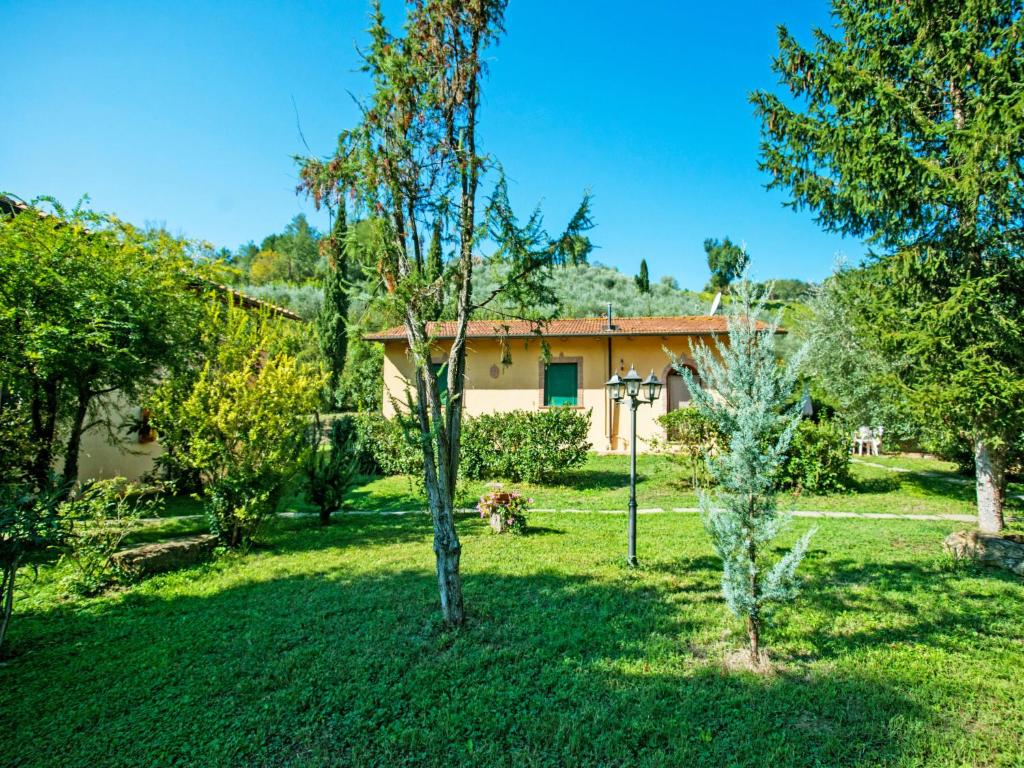 a yard with trees and a house in the background at Apartment Il Mirto by Interhome in La Collina