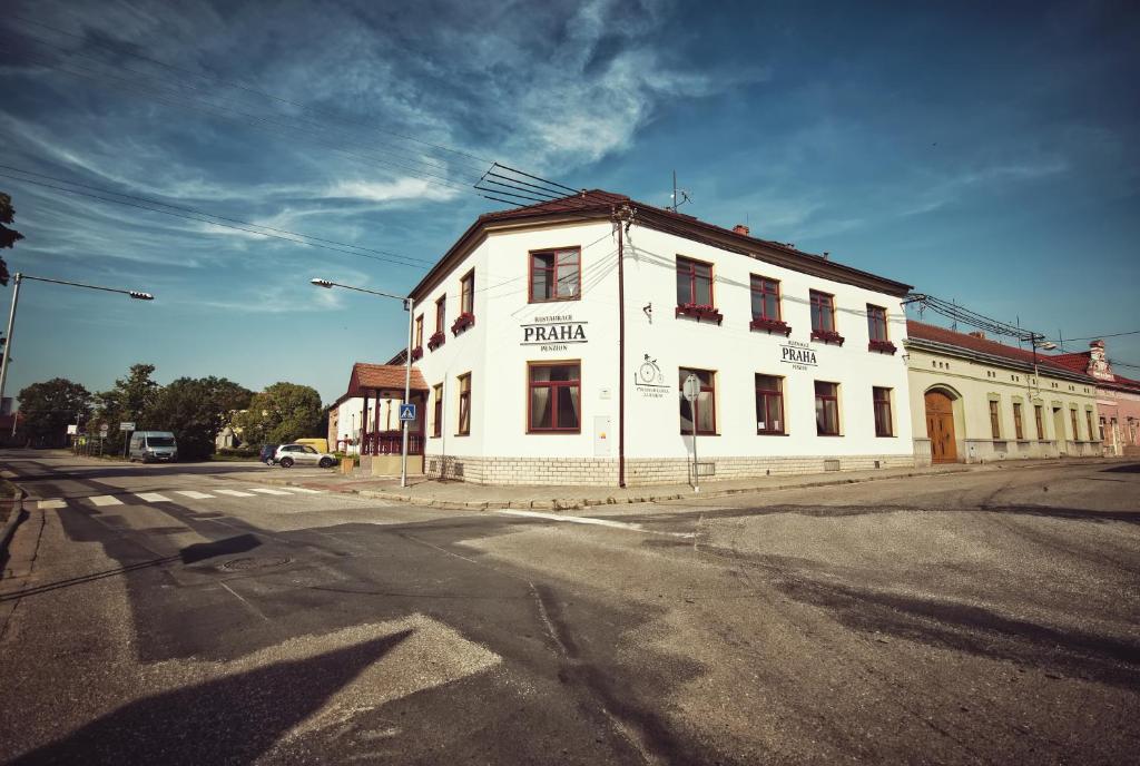 ein weißes Gebäude an der Ecke einer Straße in der Unterkunft Restaurace a Penzion Praha in Dolní Dunajovice