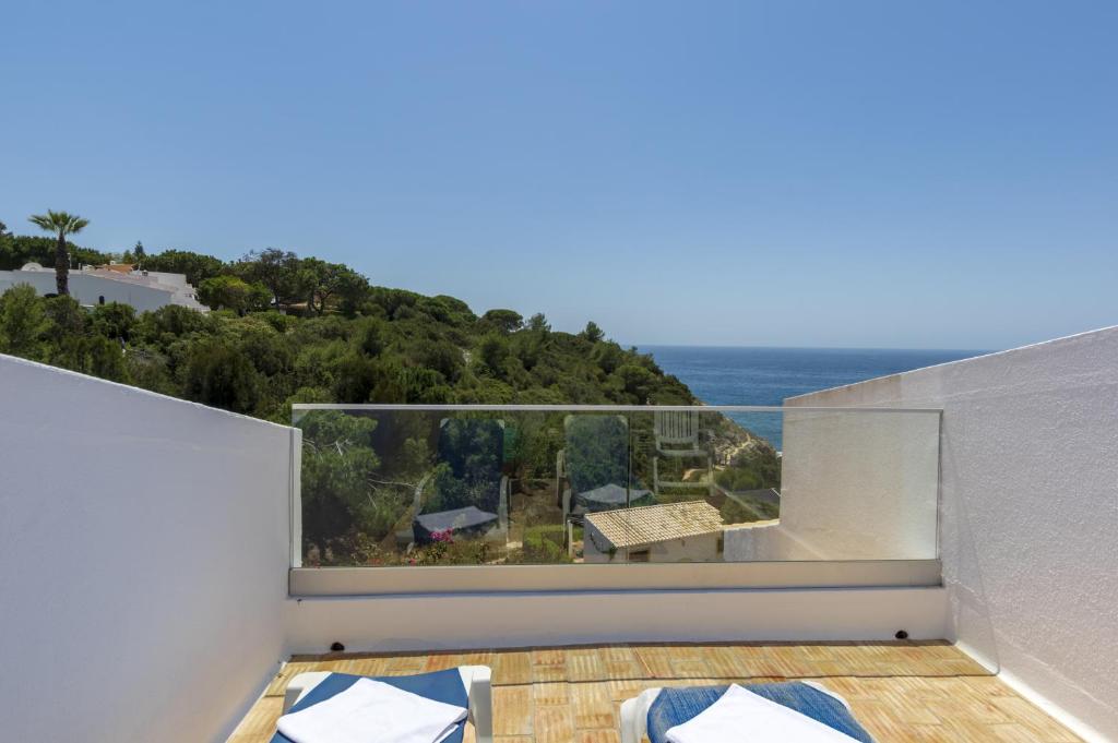 a room with a balcony with a view of the ocean at Rocha Brava Village Resort in Carvoeiro