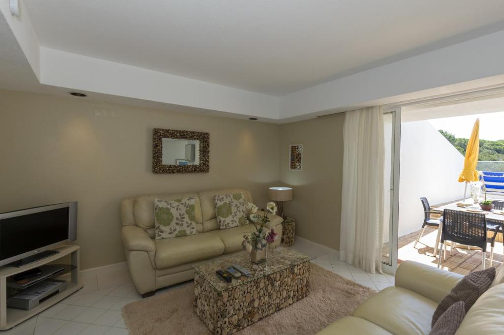 a living room with a couch and a television at Rocha Brava Village Resort in Carvoeiro