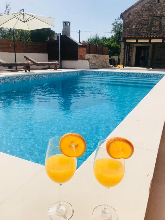 two glasses of orange juice sitting next to a swimming pool at Apartments Malic in Pridraga