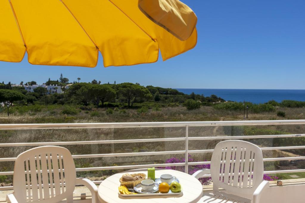 a table and chairs on a balcony with an umbrella at Rocha Brava Village Resort in Carvoeiro