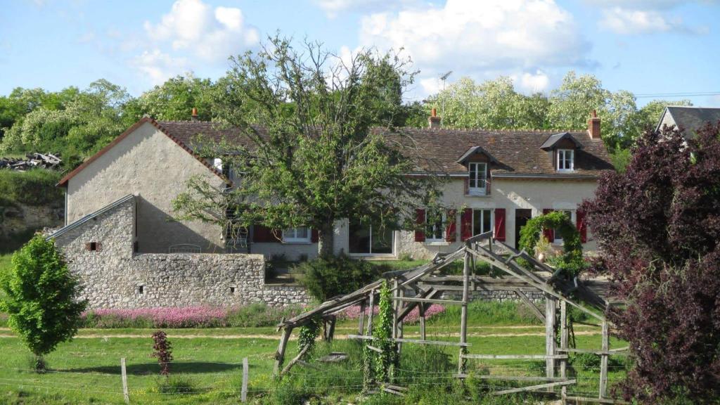 une vieille maison avec une aire de jeux devant elle dans l'établissement Ferme de Bellevue, à Landes-le-Gaulois