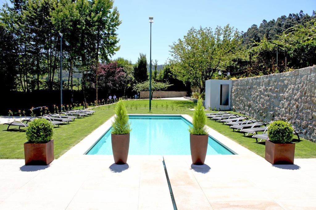 a swimming pool with potted plants in a garden at Casa do Passal Country House in Paço de Sousa
