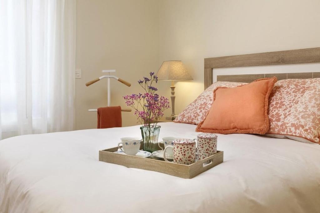bandeja con tazas y platillos en una cama en Apartamento Ravachol Pontevedra ciudad, en Pontevedra