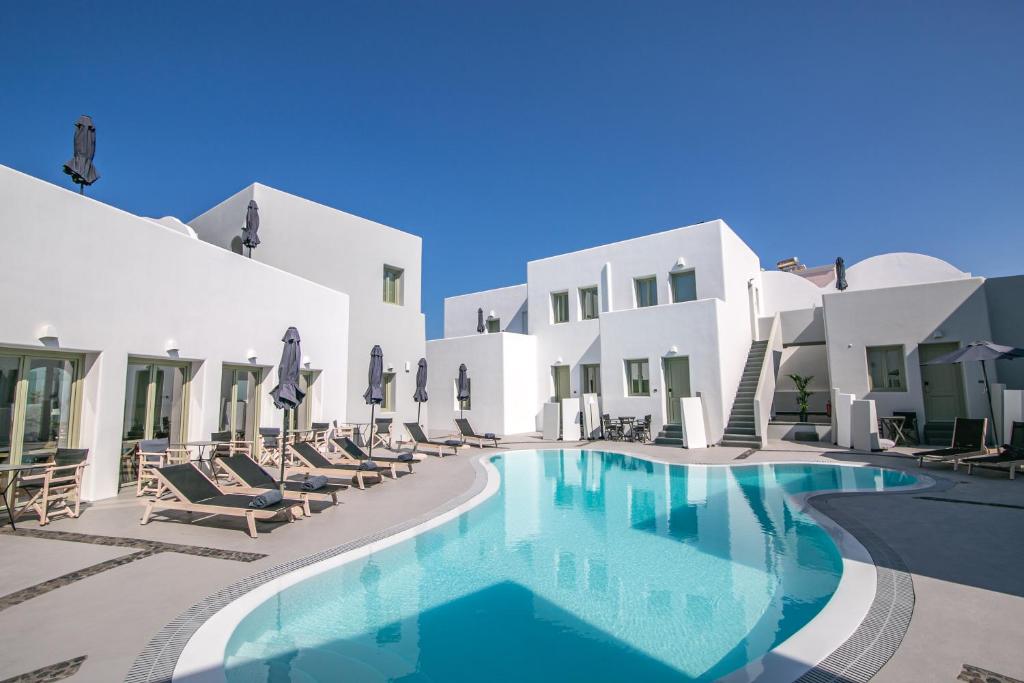 a swimming pool in front of a villa with chairs at Kallos Imar Boutique Hotel in Mesaria