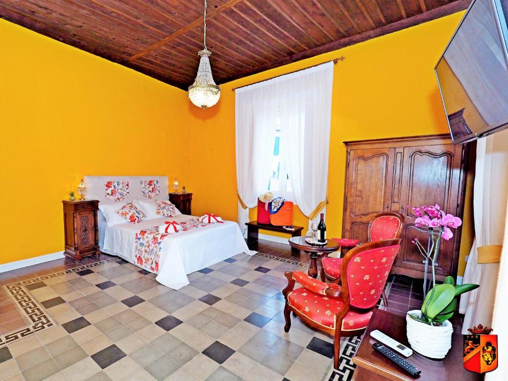 a yellow bedroom with a bed and a chair at Palazzo Toraldo di Francia in Tropea