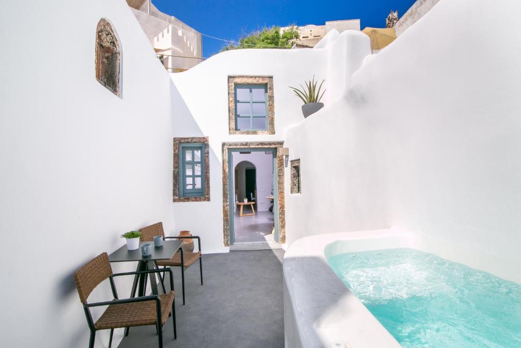 a white house with a swimming pool and chairs at Demeter Cave House - Luxury Adults Only Cave House in Pyrgos