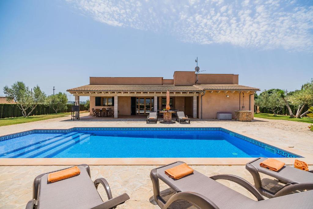 a swimming pool with two chairs and a house at Can Rua in Sa Pobla