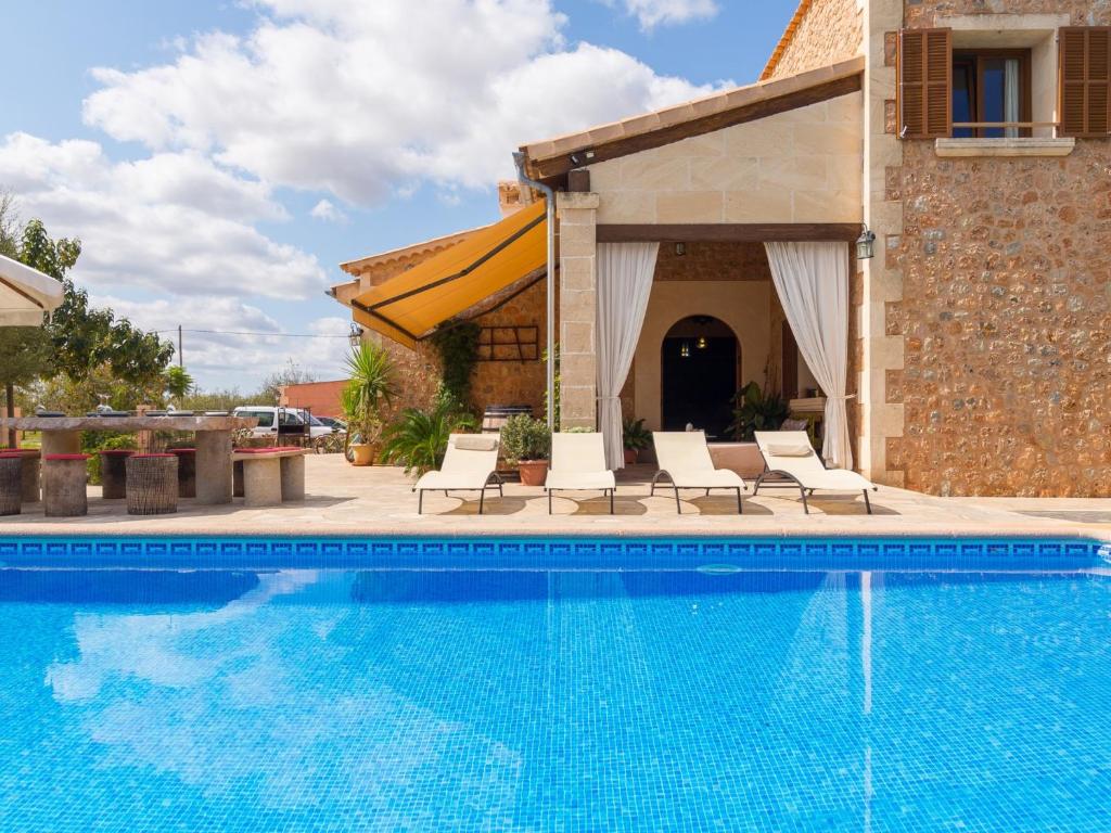 a swimming pool with chairs and a house at Es rafalot in Binissalem