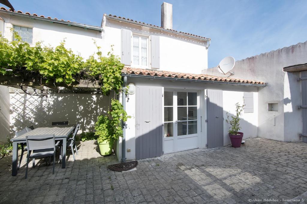 een patio met een tafel en een wit huis bij Maison Aumière in La Flotte