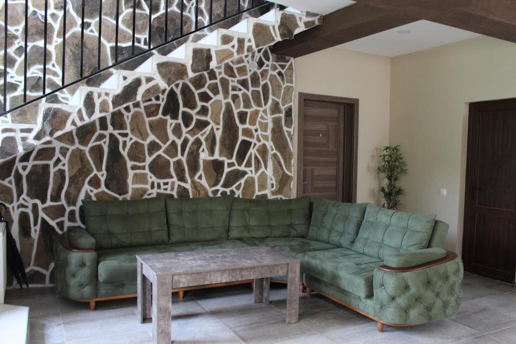 uma sala de estar com um sofá verde e uma parede de pedra em Nikala's house em Borjomi