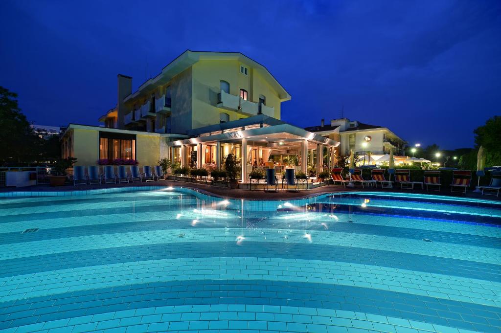 - une grande piscine en face d'un bâtiment la nuit dans l'établissement Junior Family Hotel, à Cavallino-Treporti