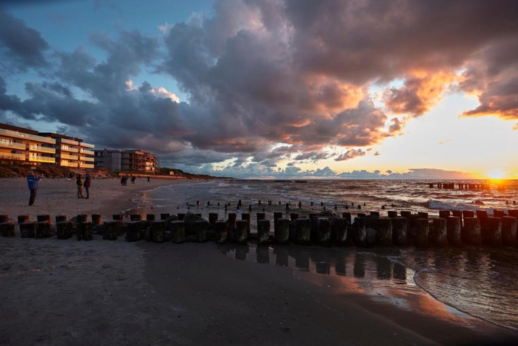 a sunset on the beach with people walking on the beach at Apartament z widokiem na morze in Dziwnów