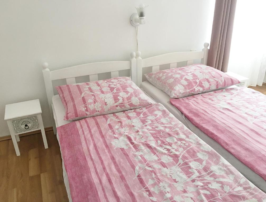 2 camas en una habitación con sábanas rosas y blancas en Balatonfenyves - Munkácsy u. 6. en Balatonfenyves