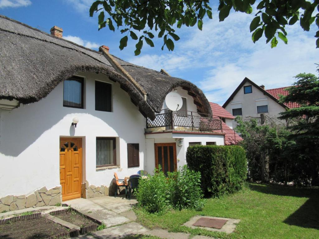 a thatch roofed house with a patio and a yard at 2+2 fős apartman Badacsonytomaj központjában in Badacsonytomaj