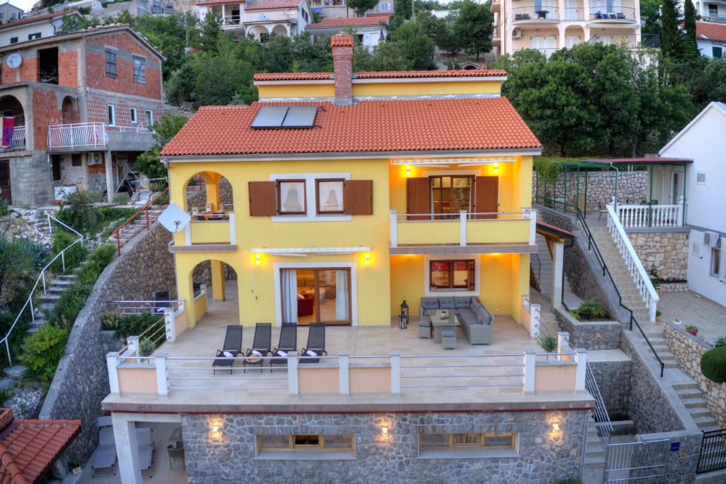 a yellow house with a deck in a city at Apartments Stipe in Lukovo
