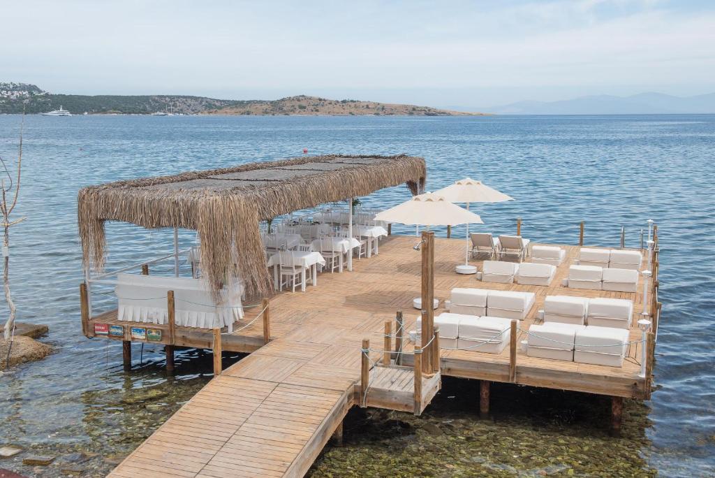 une jetée avec des chaises et des parasols sur l'eau dans l'établissement Madda Hotel, à Türkbükü