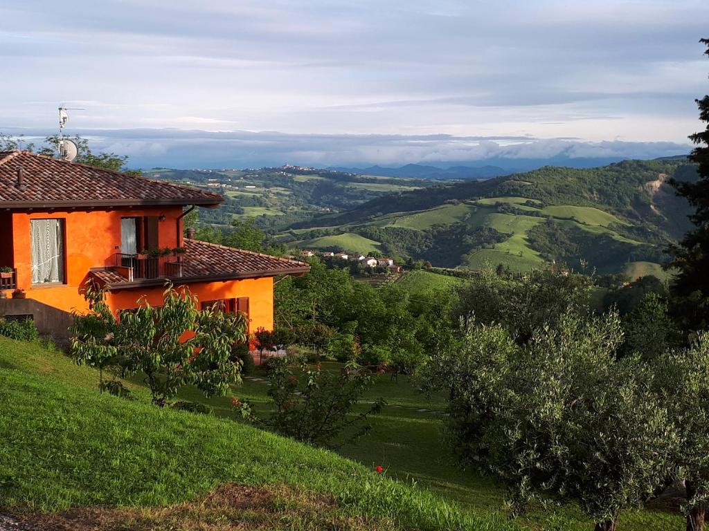 een oranje huis bovenop een groene heuvel bij APPARTAMENTO INDIPENDENTE IN VILLETTA IN BIOARCHITETTURA in Gemmano