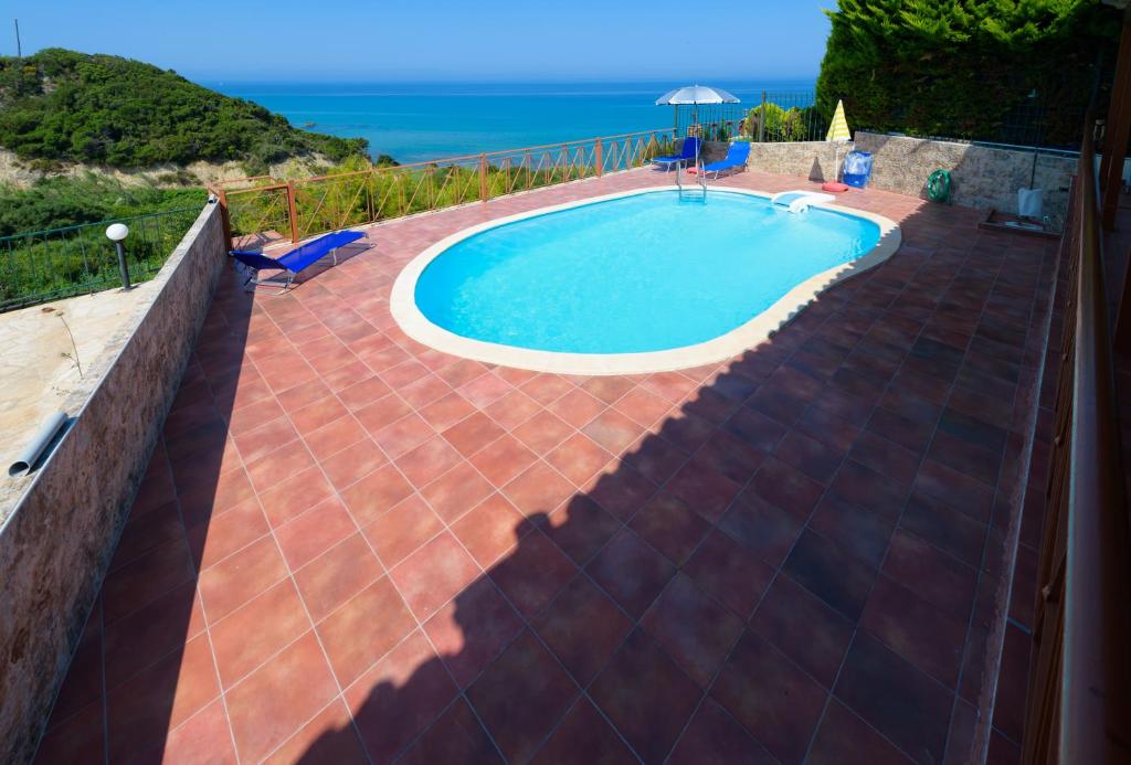 a swimming pool with a brick patio and the ocean at Analipsi House Afrodite in Kástro Tornéze