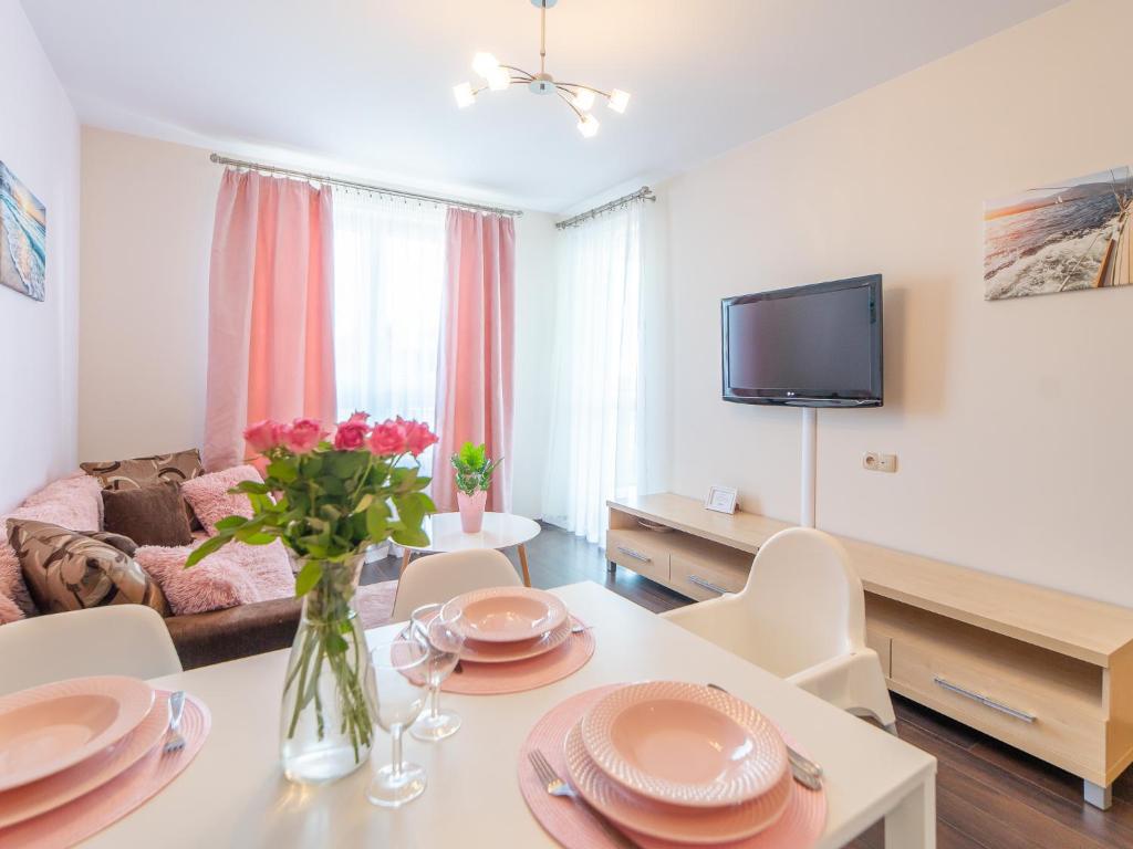 a living room with a table and chairs and a tv at Apartamenty Prywatne w Hotelu przy plaży DIVA Kołobrzeg in Kołobrzeg