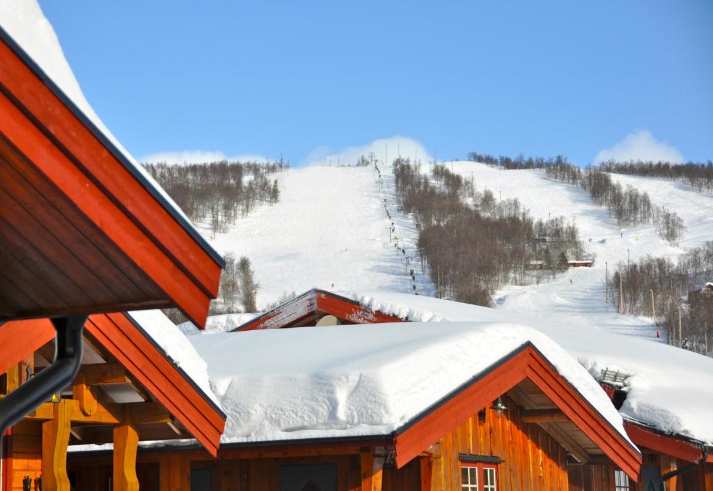 un techo cubierto de nieve de un lodge de esquí con una pista cubierta de nieve en Tunet, en Hemavan