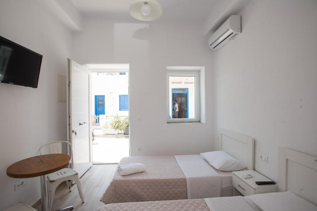 a white room with two beds and a table at Lovely Studios In Mykonos Old Town in Mýkonos City