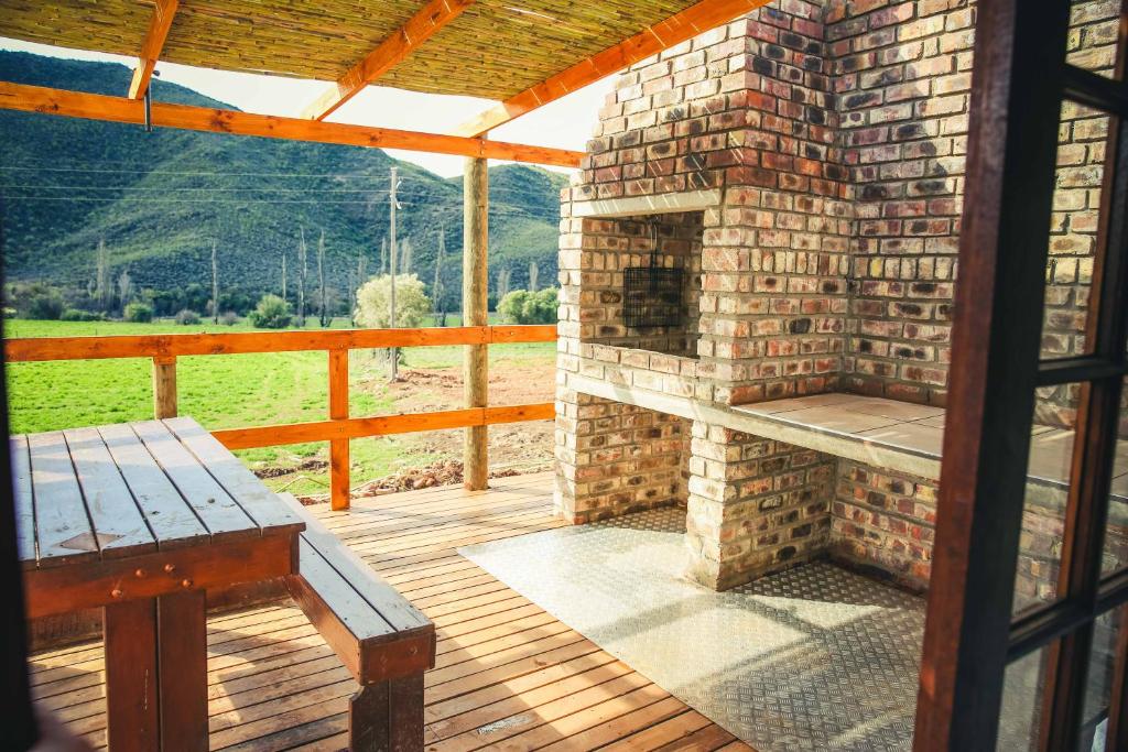 a patio with a brick fireplace and a bench at Wilgewandel Holiday Farm & Day Restaurant in Oudtshoorn