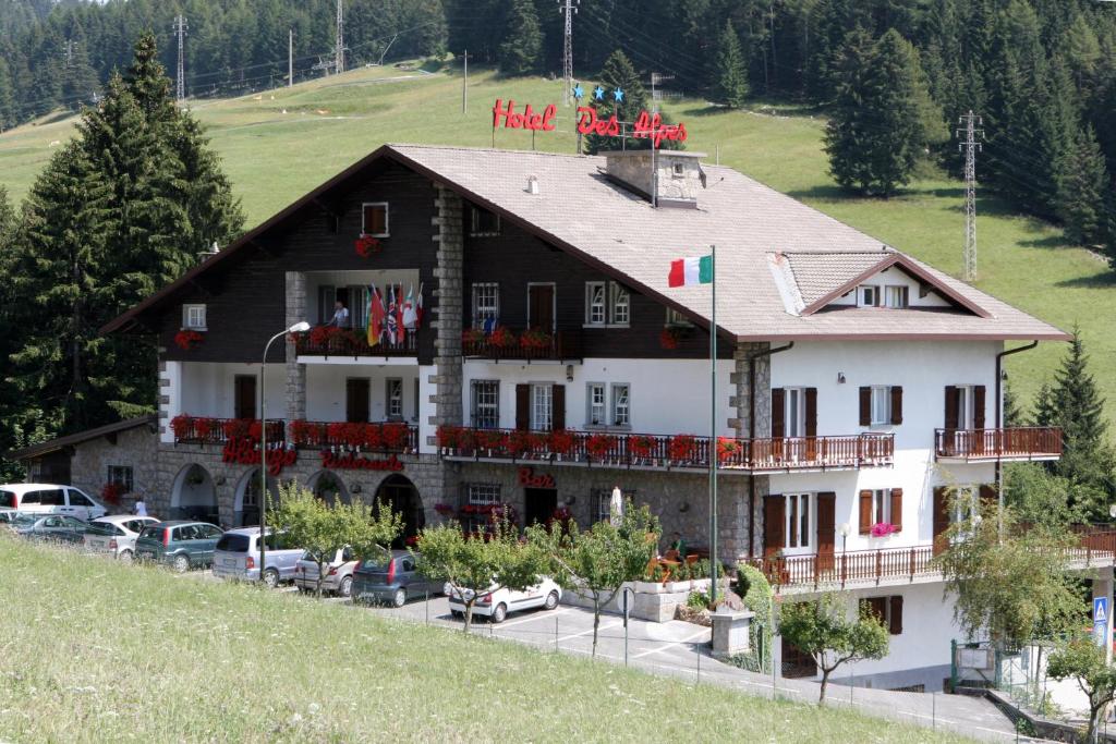 a large building with cars parked in front of it at Hotel Des Alpes in Castione della Presolana