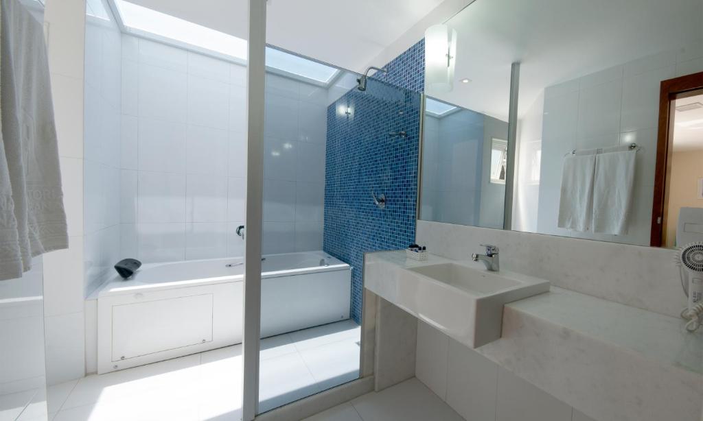 a bathroom with a shower, sink, and tub at Hotel Astoria Copacabana in Rio de Janeiro