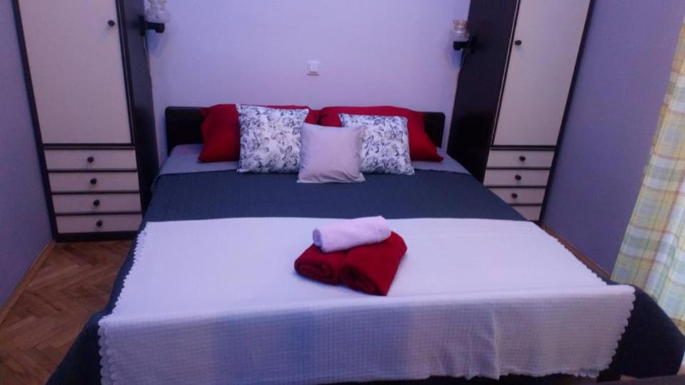 ein Schlafzimmer mit einem großen Bett mit roten und weißen Kissen in der Unterkunft Dalmatino in Brodarica