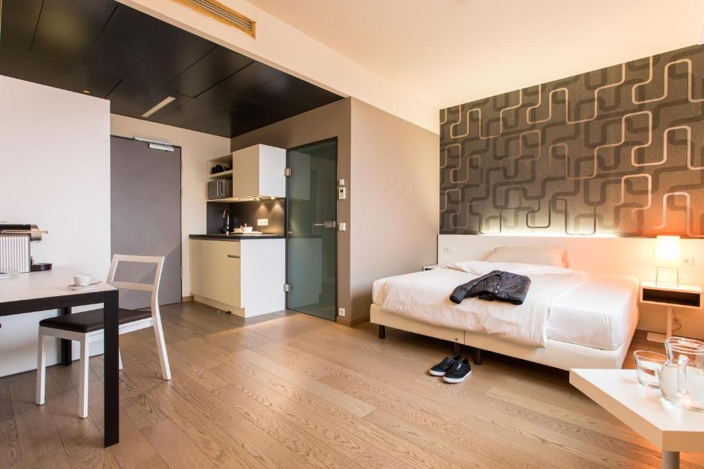 a bedroom with a bed and a table and a kitchen at harry's home hotel & apartments in Graz