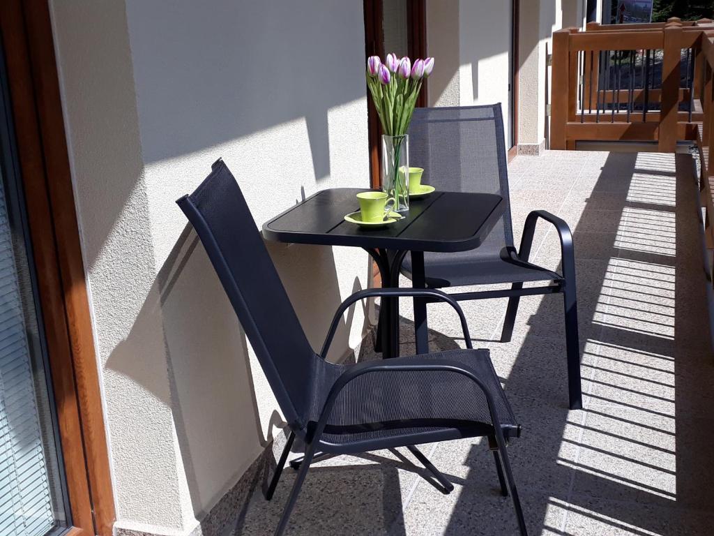 una mesa y sillas en un balcón con un jarrón de flores en Apartment Jasna - Lucky, en Demänovská Dolina