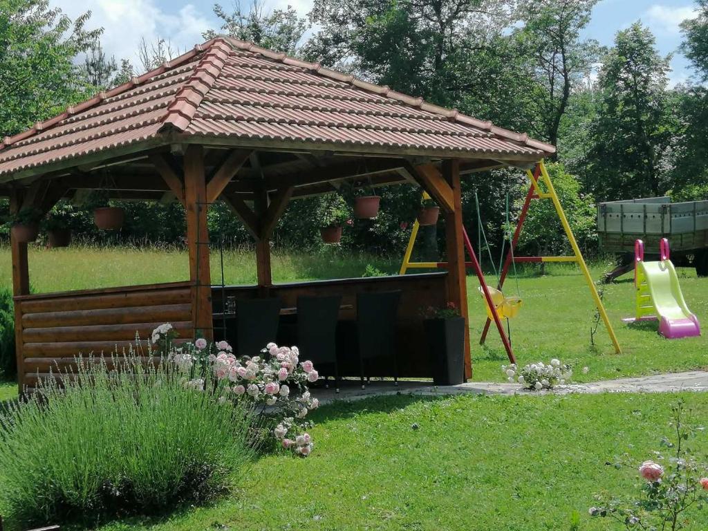 cenador de madera en un jardín con parque infantil en Nika en Ogulin