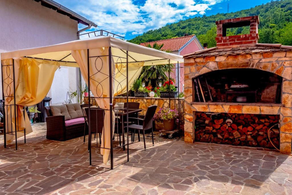 patio z kominkiem, stołem i krzesłami w obiekcie Comfortable apartment near Opatija w mieście Matulji