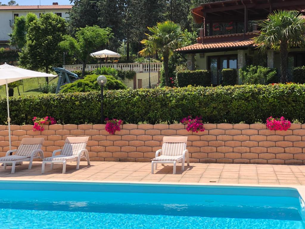 una piscina con 2 sillas y una pared de retención en Casa Vacanze Patrizia, en Montefiore dellʼAso